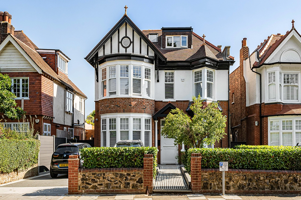 A two-storey semi-detached house with a white and brick exterior, black timber-frame accents, and a tiled path leading to the front door, flanked by hedges and brick walls.
